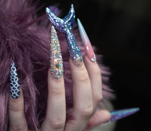 Olivia Collins
"Being a young nail tech in a small town has its challenges. I don’t often get to express myself with nail art so I took this opportunity to push myself way past my limits. This is me. I’ve never sculpted nails on myself past a number 1... these are a 4.5 which I definitely struggled with. I’ve never made any shapes out of acrylic so I tried to do my best with a mermaid tail. I don’t hand paint so I freehanded some scales, I’ve never done a full Swarovski crystal nail before but I did it. I find it hard to express myself in a small town sometimes but I think I exceeded all of my own personal expectations with this project."