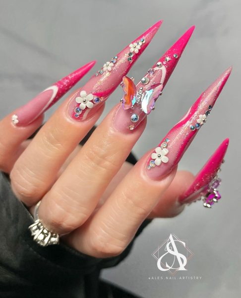Florida nail artist, @ales.nail.artistry, makes an impact with stiletto enhancements, adorned with floral and butterfly embellishments.