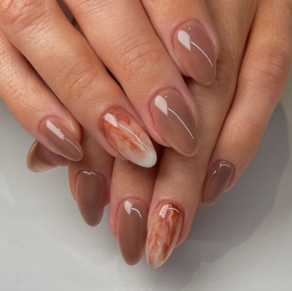 Katie Masters (@nailthoughts) goes glossy for her latte design, creating a marble feature nail to draw attention. 